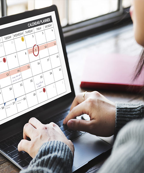 person typing into a calendar on their computer